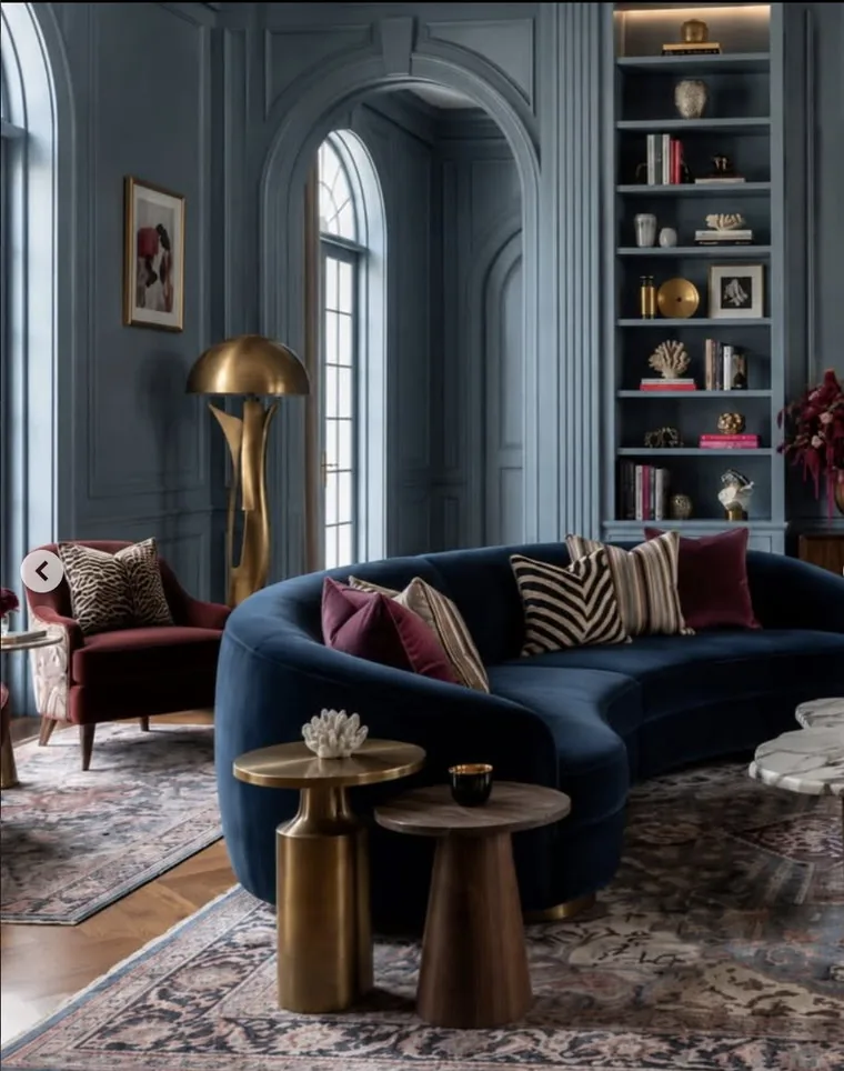 Panelled drawing room with curved navy velvet sofa, brass lighting and antique rug